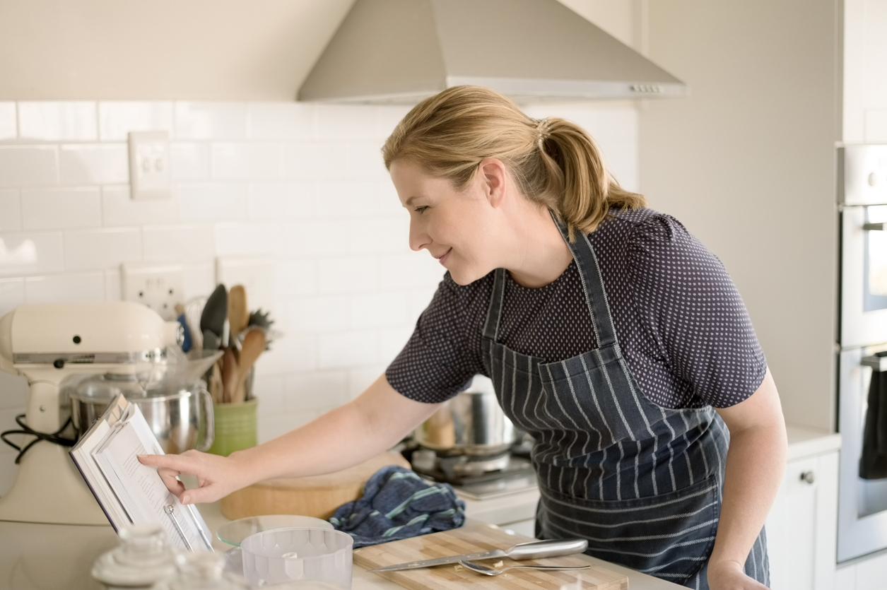 Mature woman reading cookbook in the kitchen.