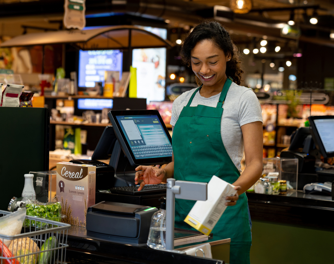 Happy cashier working at the supermarket ringing up groceries